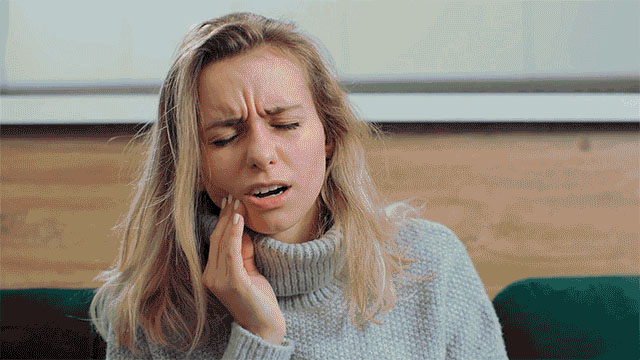 Woman experiencing discomfort or pain in her cheek/mouth area
